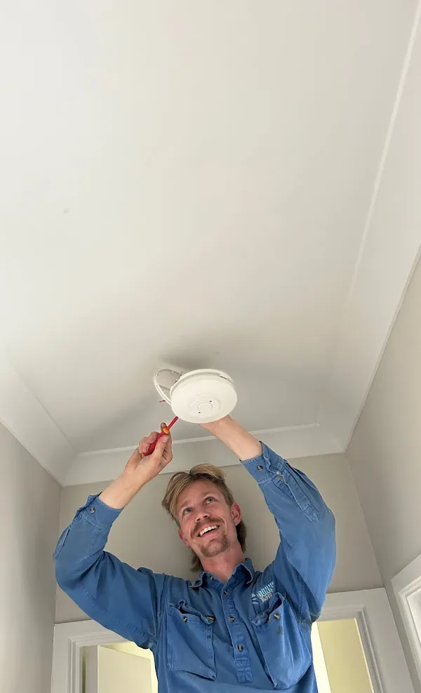 Connex Electrical electrician installing a photoelectric smoke alarm in a Brisbane home