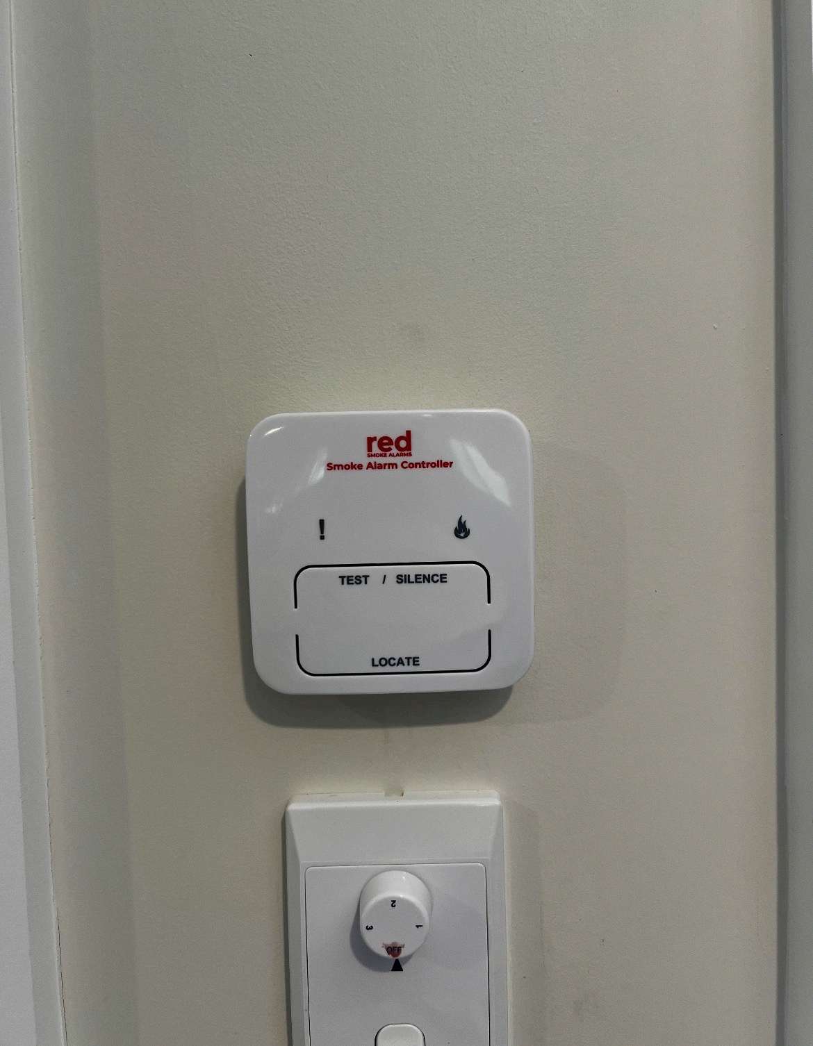 Wall-mounted red Smoke Alarm Controller with test, silence and locate buttons installed by Connex Electrical in a North Brisbane home